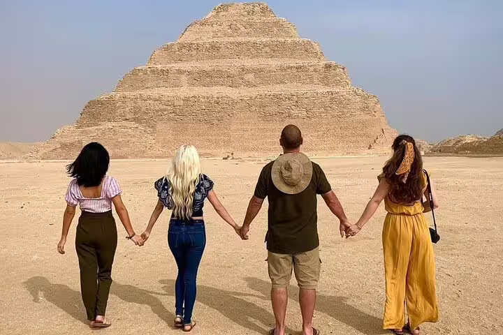 Group holding hands facing Saqqara Step Pyramid on Cairo luxury adventure tour to Memphis and Dahshur