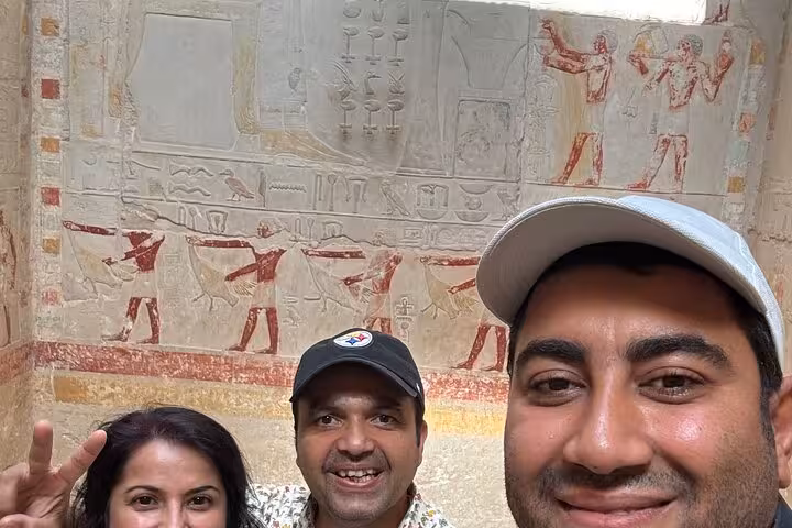 Guests selfie in Saqqara necropolis tomb, viewing ancient Egyptian wall art on Cairo private day tour