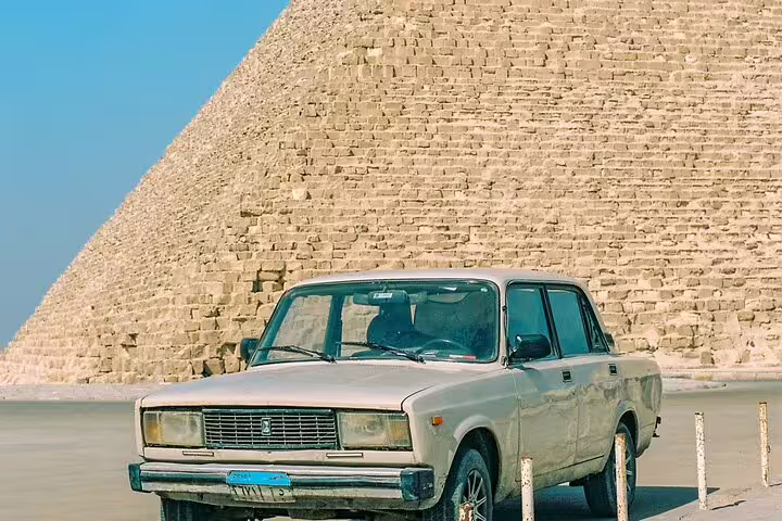 Classic car parked by the Great Pyramid of Giza, a must-see stop on a 2-day Cairo short break package