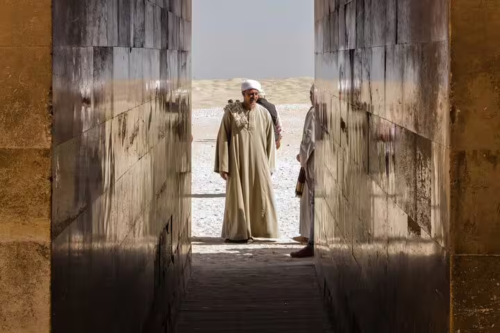 Local guide in traditional dress at Saqqara entrance passage, cultural stop on 5-day Cairo short break tour
