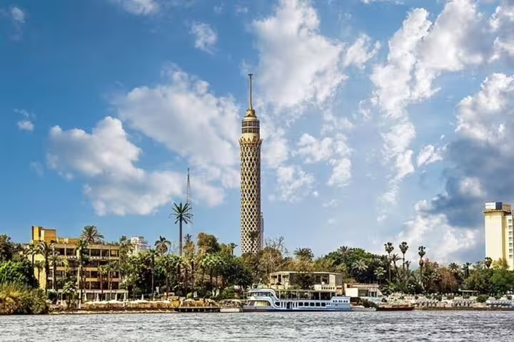 Cairo Tower rising above the Nile River with palm-lined banks, a highlight of the Manial Palace day tour