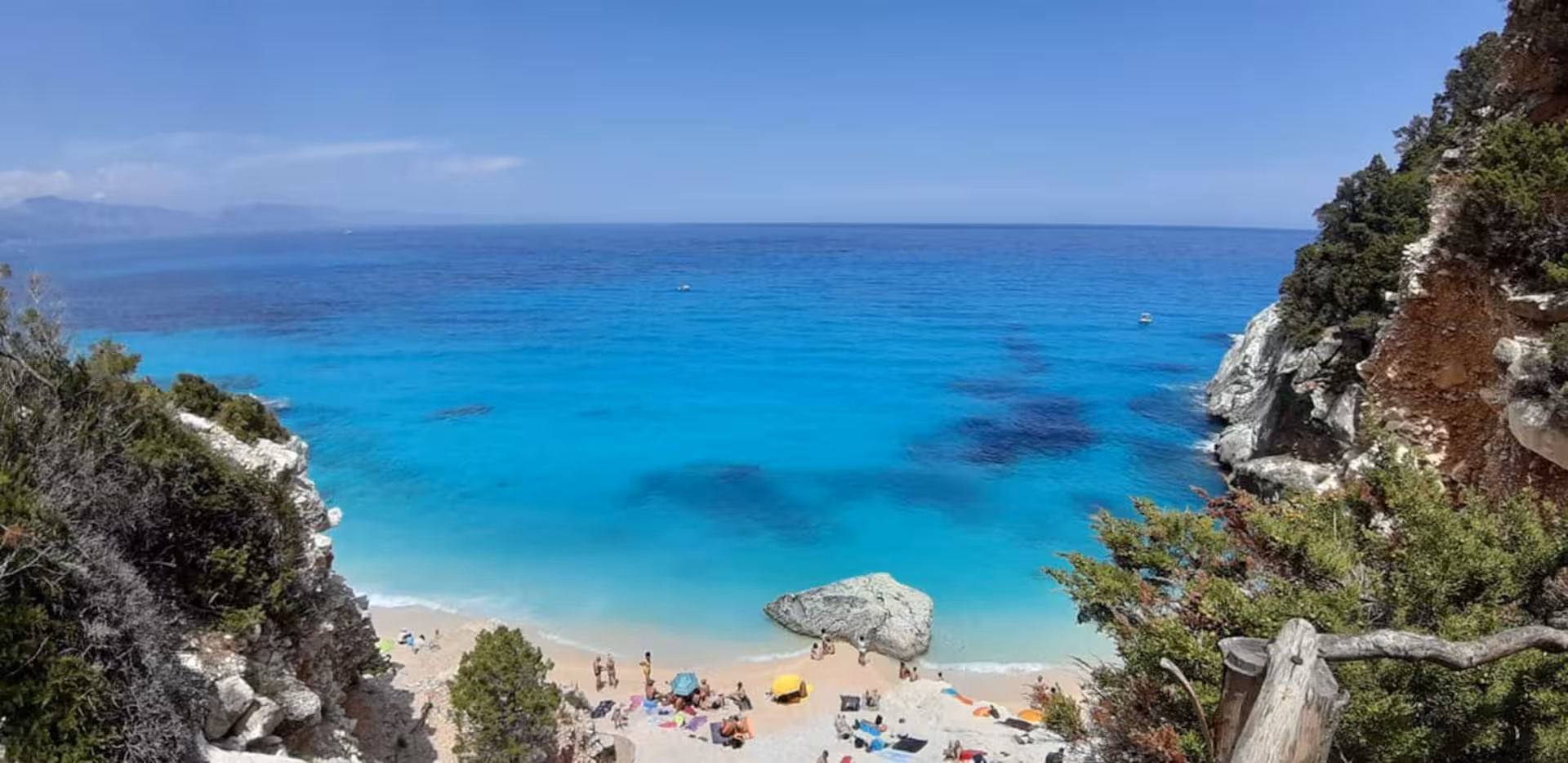 Pristine Cala Goloritzè beach with azure waters and sunbathers, perfect for a Sardinian trekking adventure.