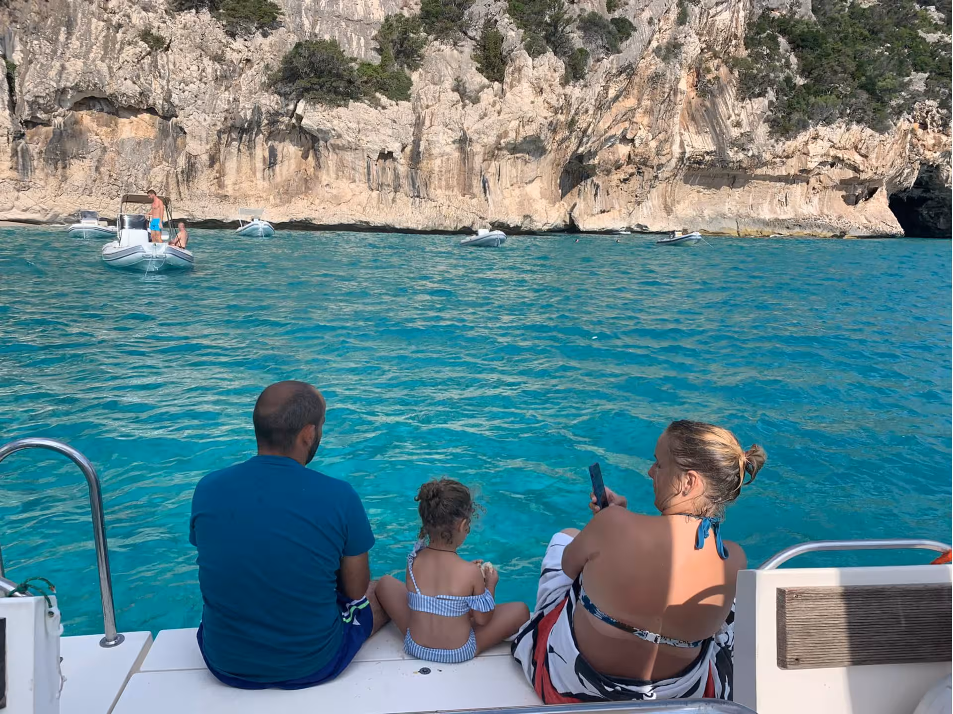 Family admiring the rocky coastline from a boat in the Gulf of Orosei, experiencing the beauty of Sardinia’s waters.