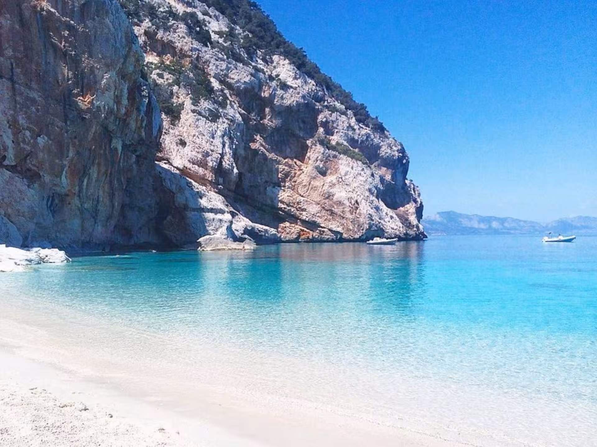 Scenic view of Cala Gonone's turquoise waters and rocky cliffs on a sunny day in the Gulf of Orosei.