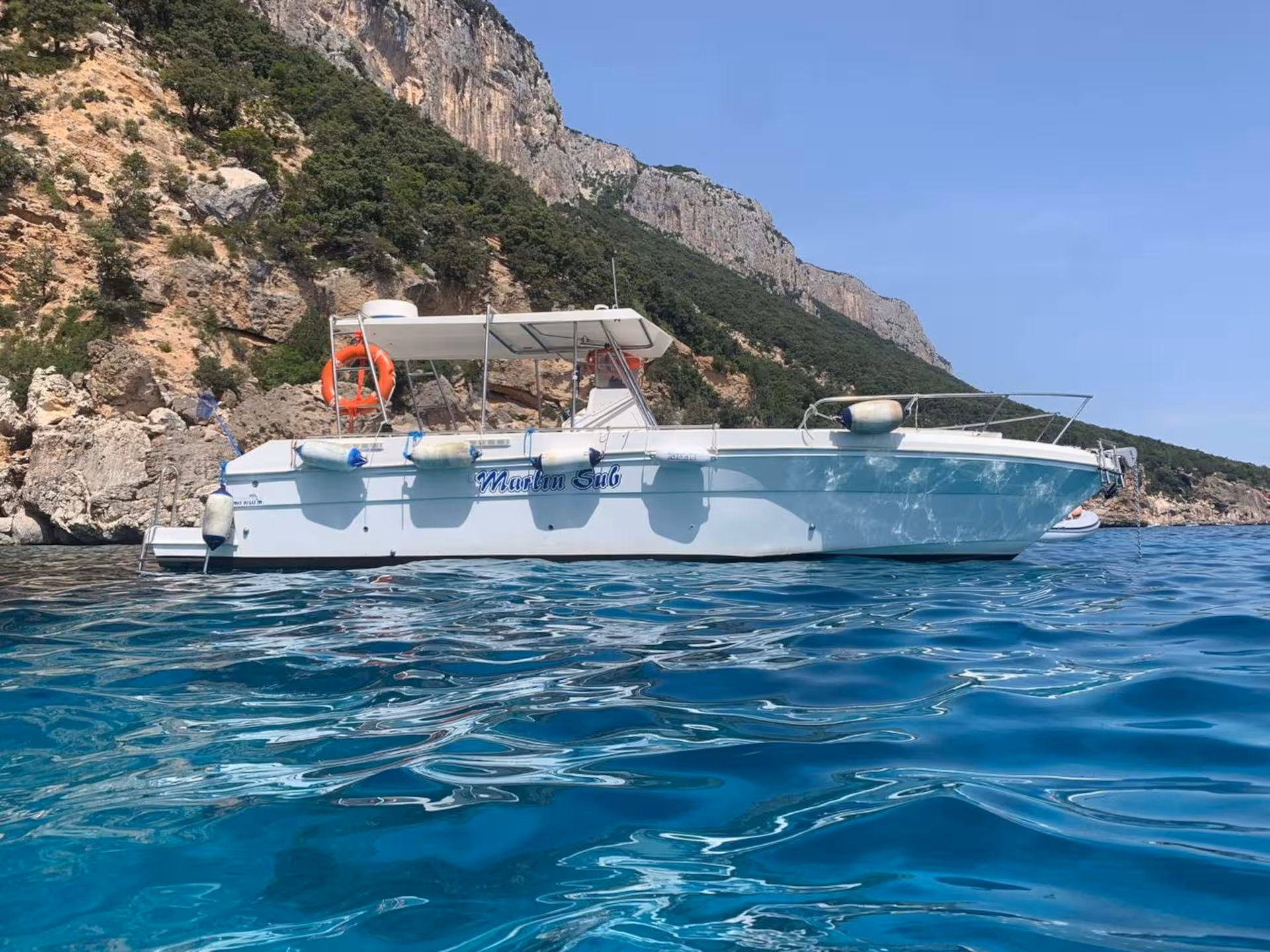 Pristine beach with crystal-clear waters and rocky coastline in the Gulf of Orosei, ideal for boat trips.