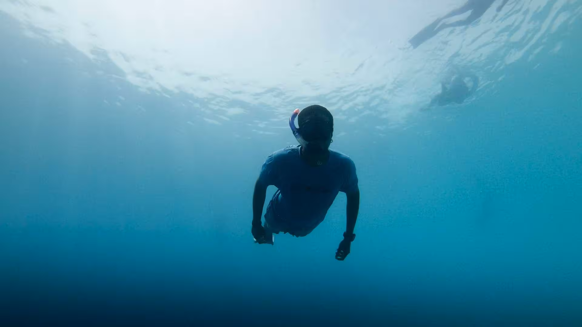 Snorkeler glides through the serene depths of Cala Gonone, Orosei Gulf, capturing the tranquility of the sea.