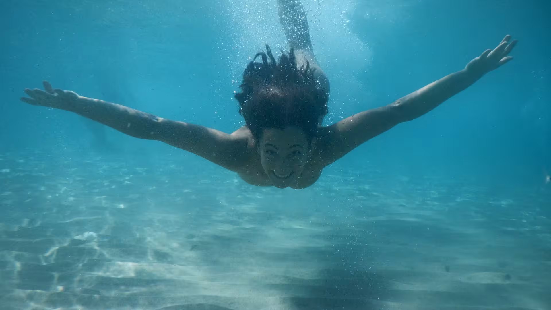 Woman enjoying snorkeling in the crystal-clear waters of Orosei Gulf, Cala Gonone, surrounded by marine life.