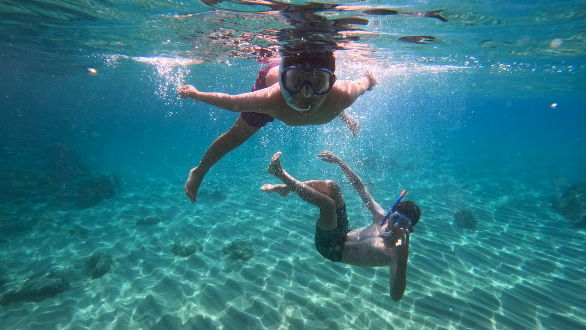 Two snorkelers explore the crystal-clear waters of Cala Gonone in the Orosei Gulf, showcasing vibrant underwater life.