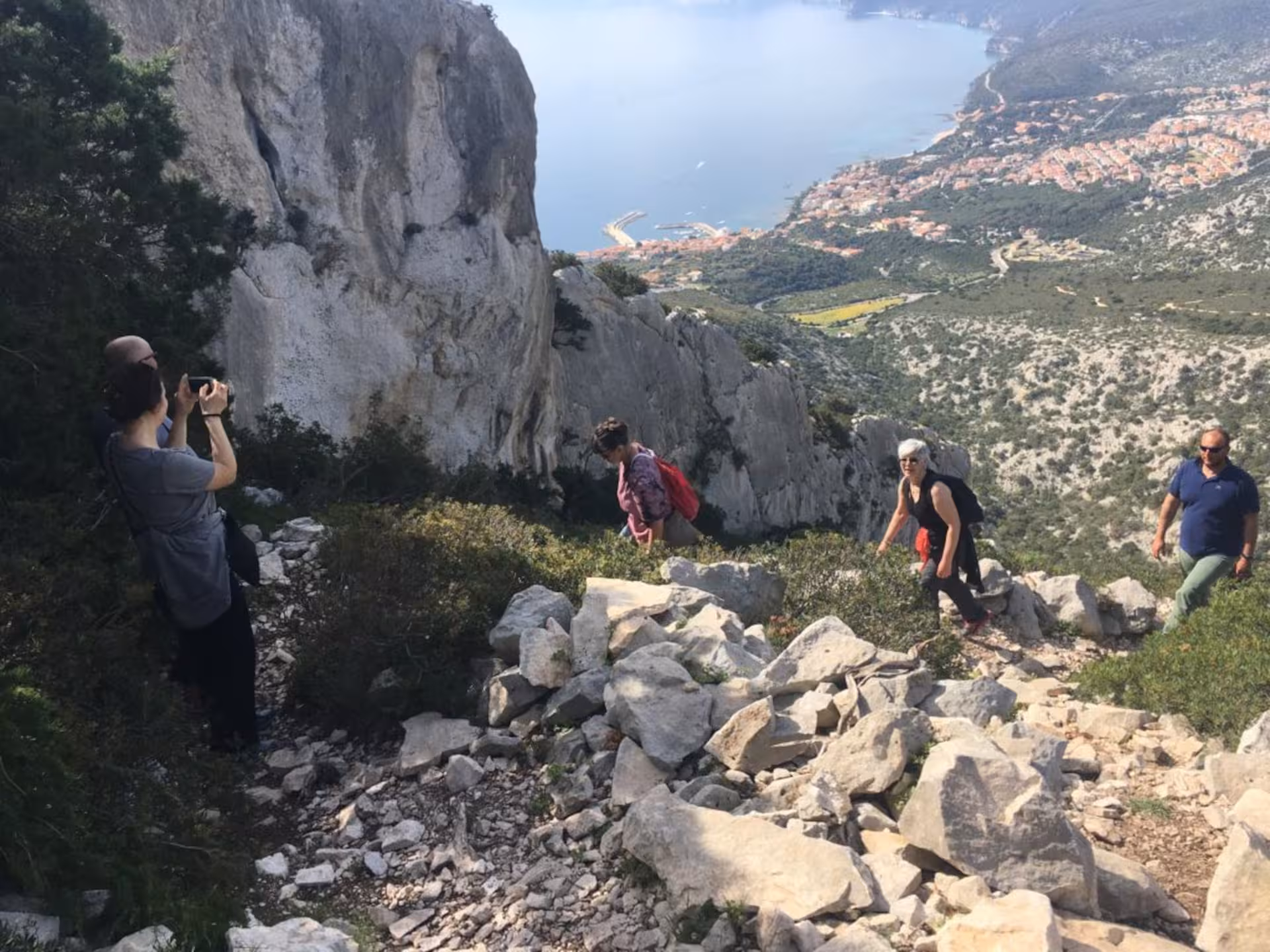 Hikers traverse rocky paths with stunning coastal views on the Supramonte Jeep tour from Cala Gonone.