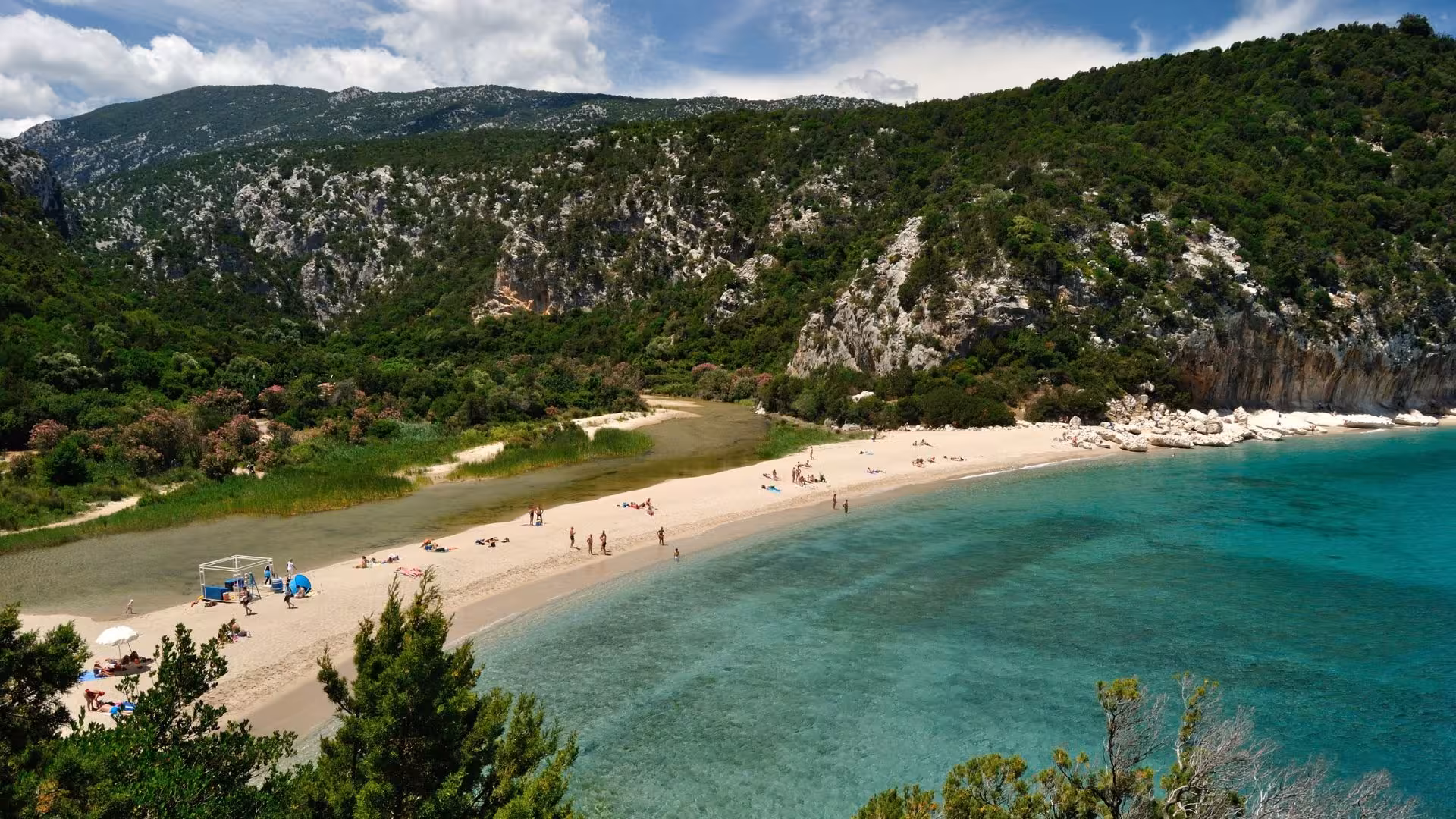 Aerial view of the pristine Cala Luna beach with crystal-clear turquoise waters and lush green cliffs in Sardinia.