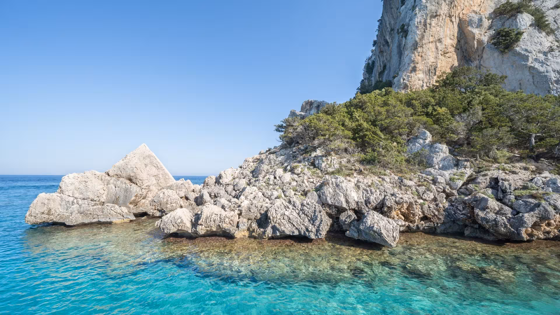 Rocky coastline with turquoise waters at Cala Luna, ideal for a scenic motorboat transfer from Cala Gonone.