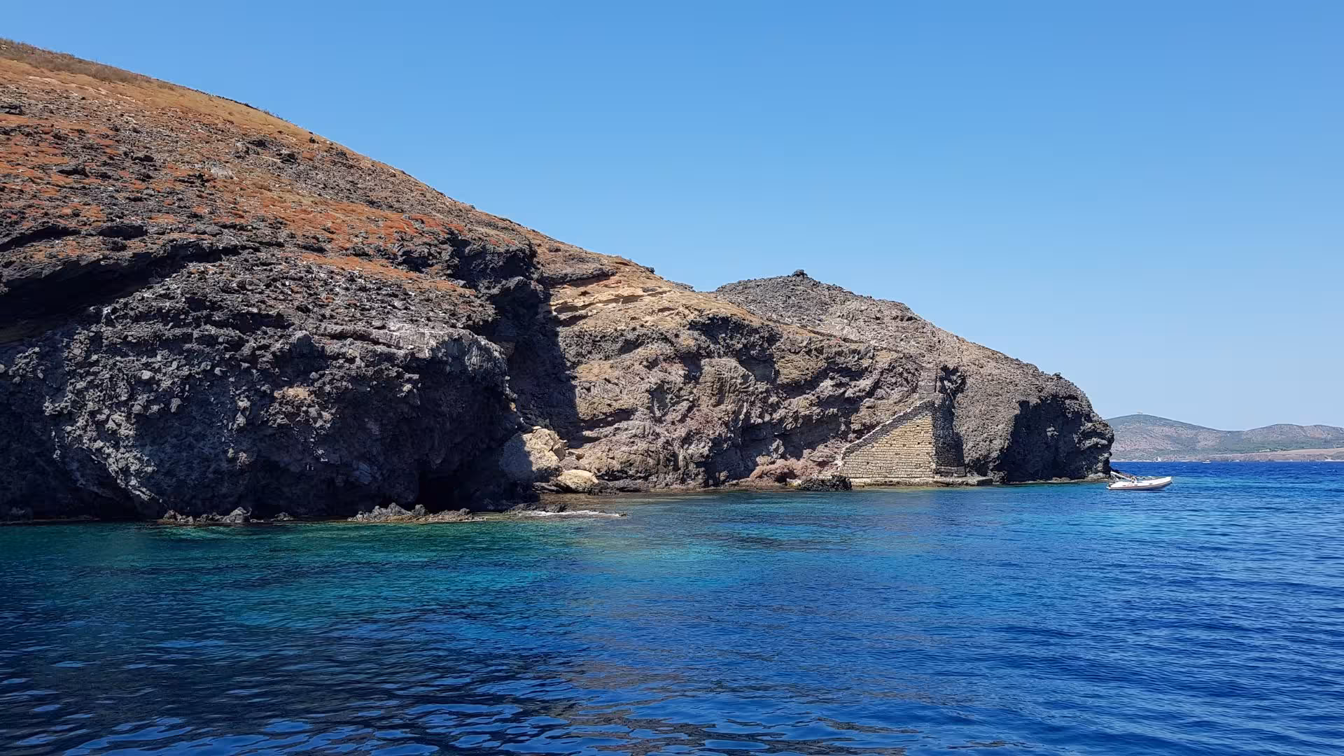 Stunning rocky coastline of San Pietro Island with crystal-clear blue waters seen from a Calasetta boat tour.