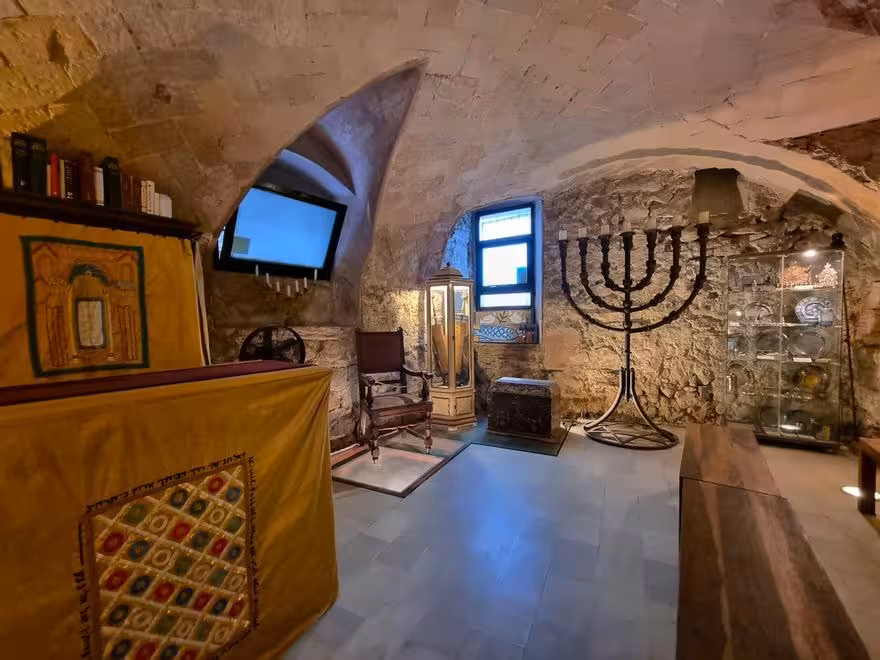 Historic room in Call de Barcelona with menorah and ancient artifacts for Jewish heritage tour.