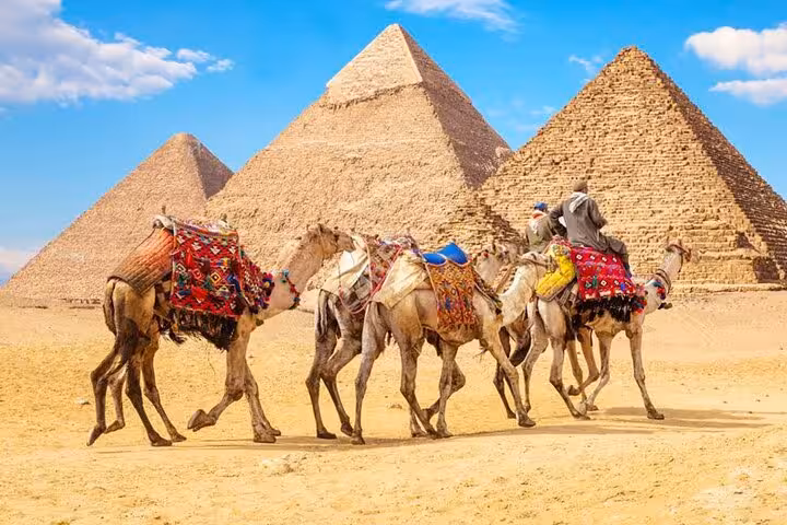 Camel caravan with riders at the Pyramids of Giza on Cairo day trip by bus from Sharm El Sheikh