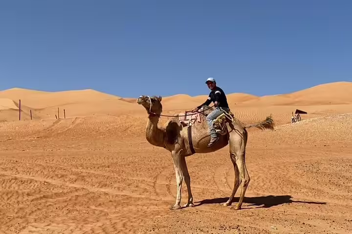 Explorer rides camel across expansive desert landscape on an adventure tour.