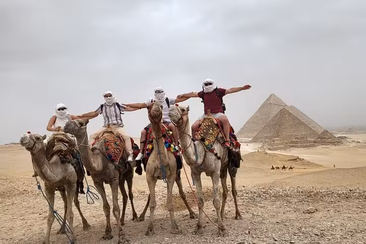 Camel ride group at Giza Plateau with pyramids backdrop on Hurghada to Cairo day trip and Grand Egyptian Museum