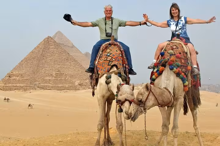 Camel ride at Giza Pyramids during Cairo day trip tour, desert view and classic pyramid backdrop with lunch