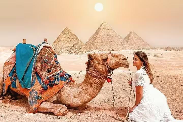 Camel ride photo stop with Giza Pyramids in background on Cairo and Pyramids bus tour from Sharm