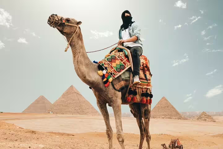 Camel ride at Giza Pyramids on private Cairo tour, desert view with three pyramids in background