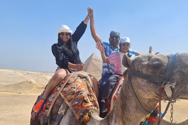 Tourists on a camel ride celebrate near the pyramids, showcasing adventure on the Private 3 Days Pyramids Tour in Egypt.