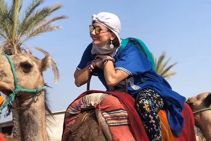 Tourist riding a camel in Sharm El Sheikh desert, Bedouin-style safari stop with palm trees and sunshine
