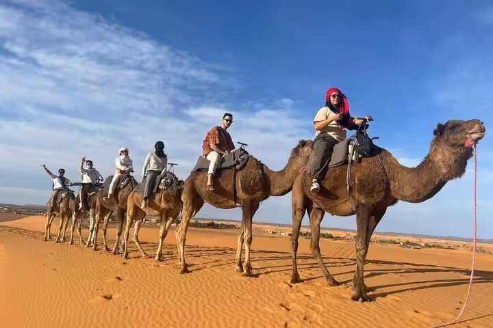 Group camel trek through the stunning Sahara dunes in Merzouga during a 3-day luxury desert tour from Fes to Marrakech.