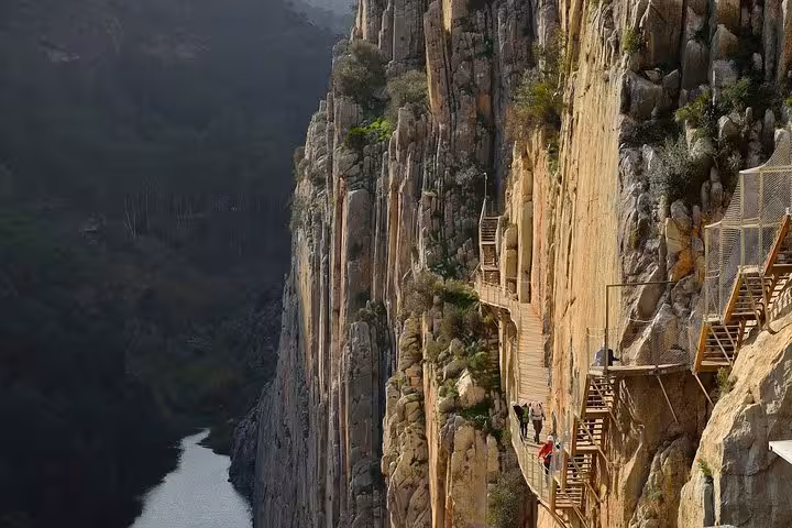Daring hikers navigate the cliffside walkway of Caminito del Rey, a thrilling tour experience from Malaga.