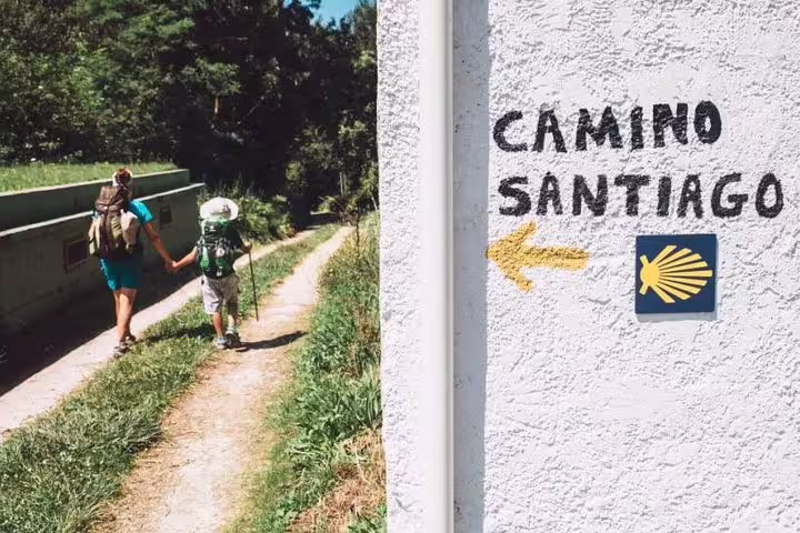 Travelers on the Camino de Santiago trail, guided by a yellow arrow, symbolizing the pilgrimage route from Porto.