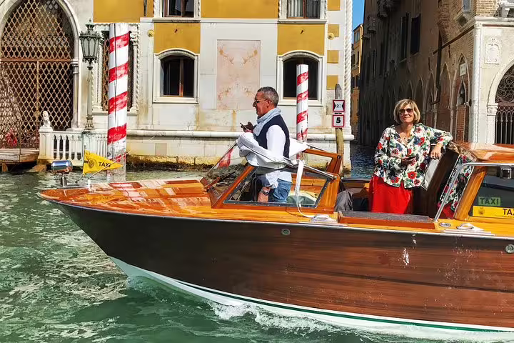 Tourists enjoying a sunny ride on a classic wooden boat along the picturesque Canal Grande in Venice.