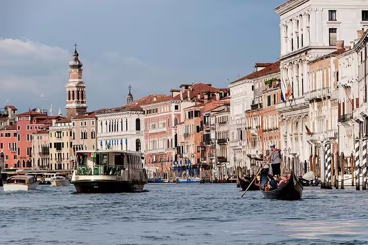 Scenic view of gondolas and water taxis navigating the bustling Canal Grande, lined with historic Venetian architecture.