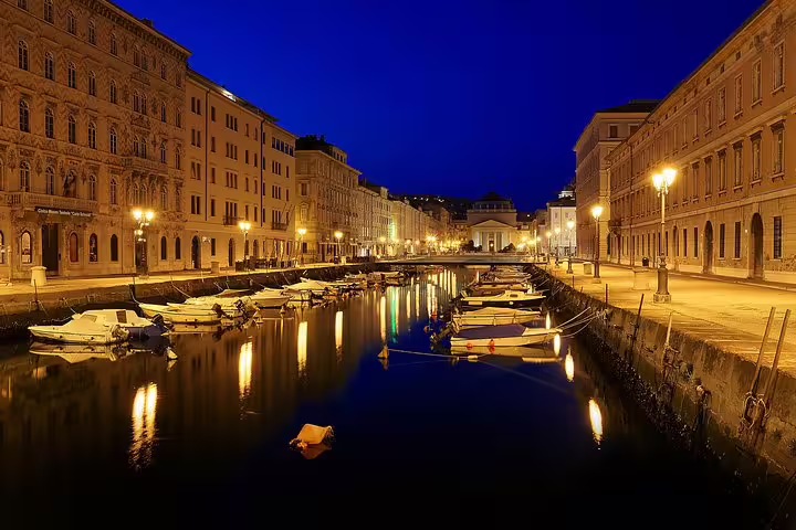 Canal Grande in Trieste at blue hour with moored boats, historic palaces and streetlights on a private evening walking tour