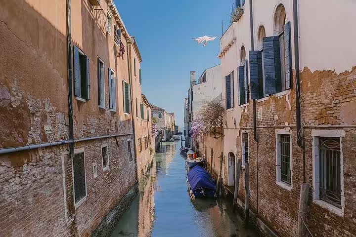 Peaceful canal in Cannaregio, Venice with rustic buildings and boats reflecting the district's historic charm.