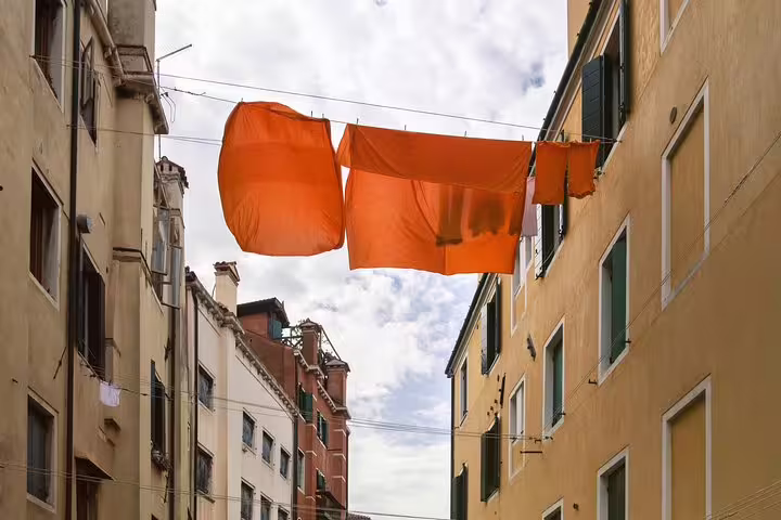 Vibrant orange laundry hangs between buildings in Cannaregio, adding color to the historic Jewish Ghetto scenery.