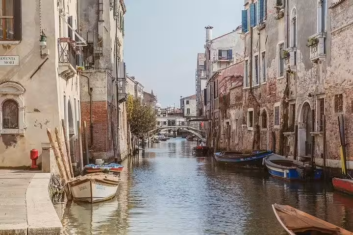 Quaint canal view in Cannaregio, Venice featuring traditional boats and picturesque bridges in the Jewish Ghetto.