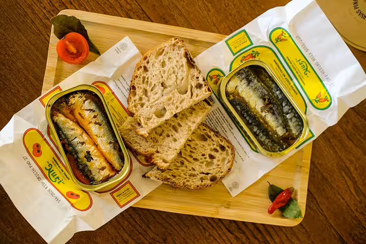 Assorted canned fish and rustic bread on a wooden platter, showcasing local flavors for the Only Fish Market Tasting Tour.