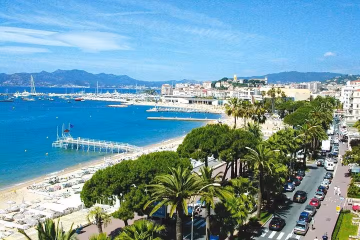 Cannes beachfront promenade lined with palm trees and vibrant blue waters of the French Riviera.