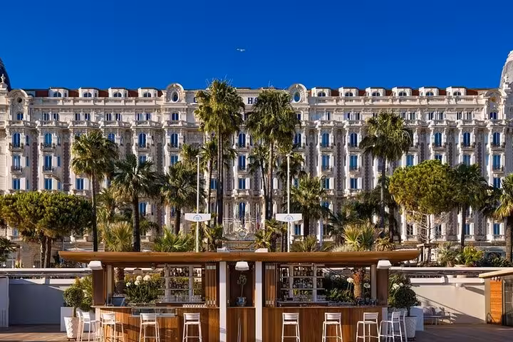 Elegant hotel facade surrounded by palm trees in Cannes, a highlight of the private shore excursion tour.