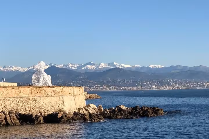 Breathtaking seascape in Cannes with a prominent sculpture and distant Alps, highlighting the beauty of Southern France.