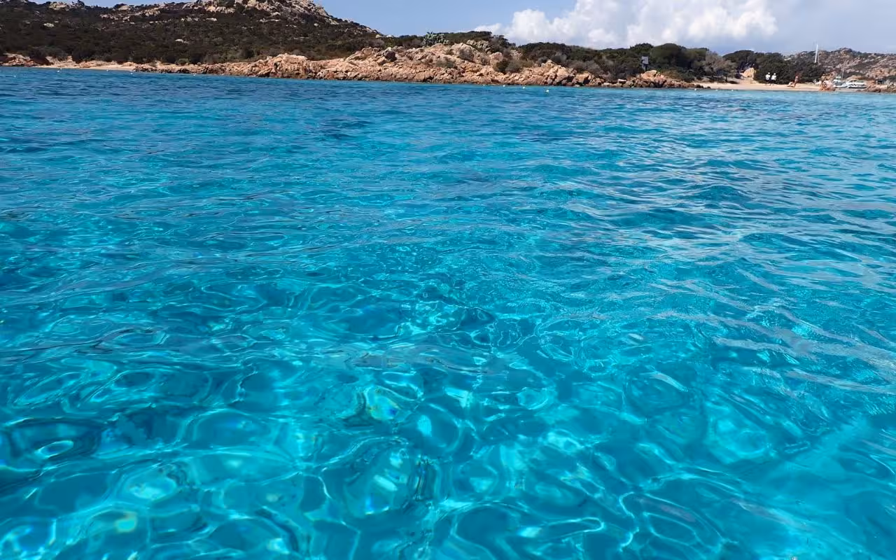Pristine azure waters and rocky landscapes of La Maddalena Archipelago, a highlight of Cannigione catamaran tours.