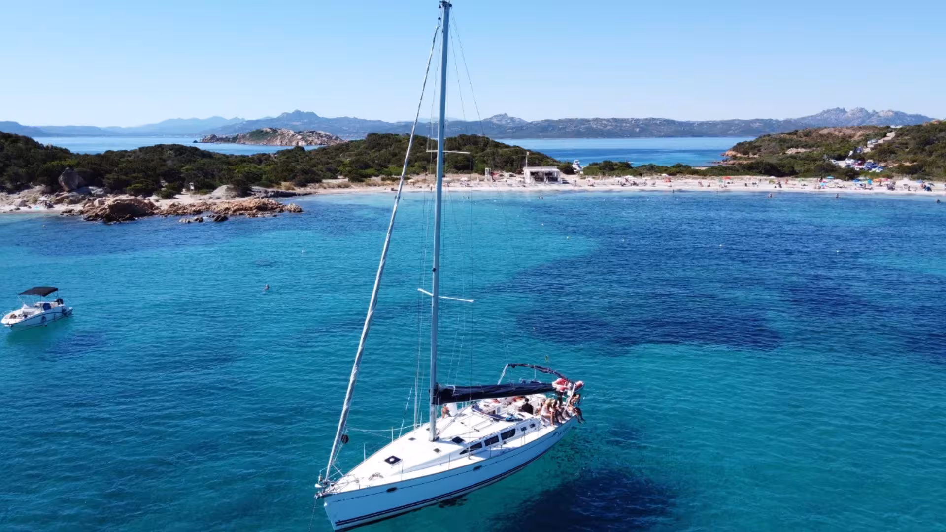 Sailboat anchored near a pristine beach in La Maddalena Archipelago, ideal for a full-day Cannigione sailing adventure.