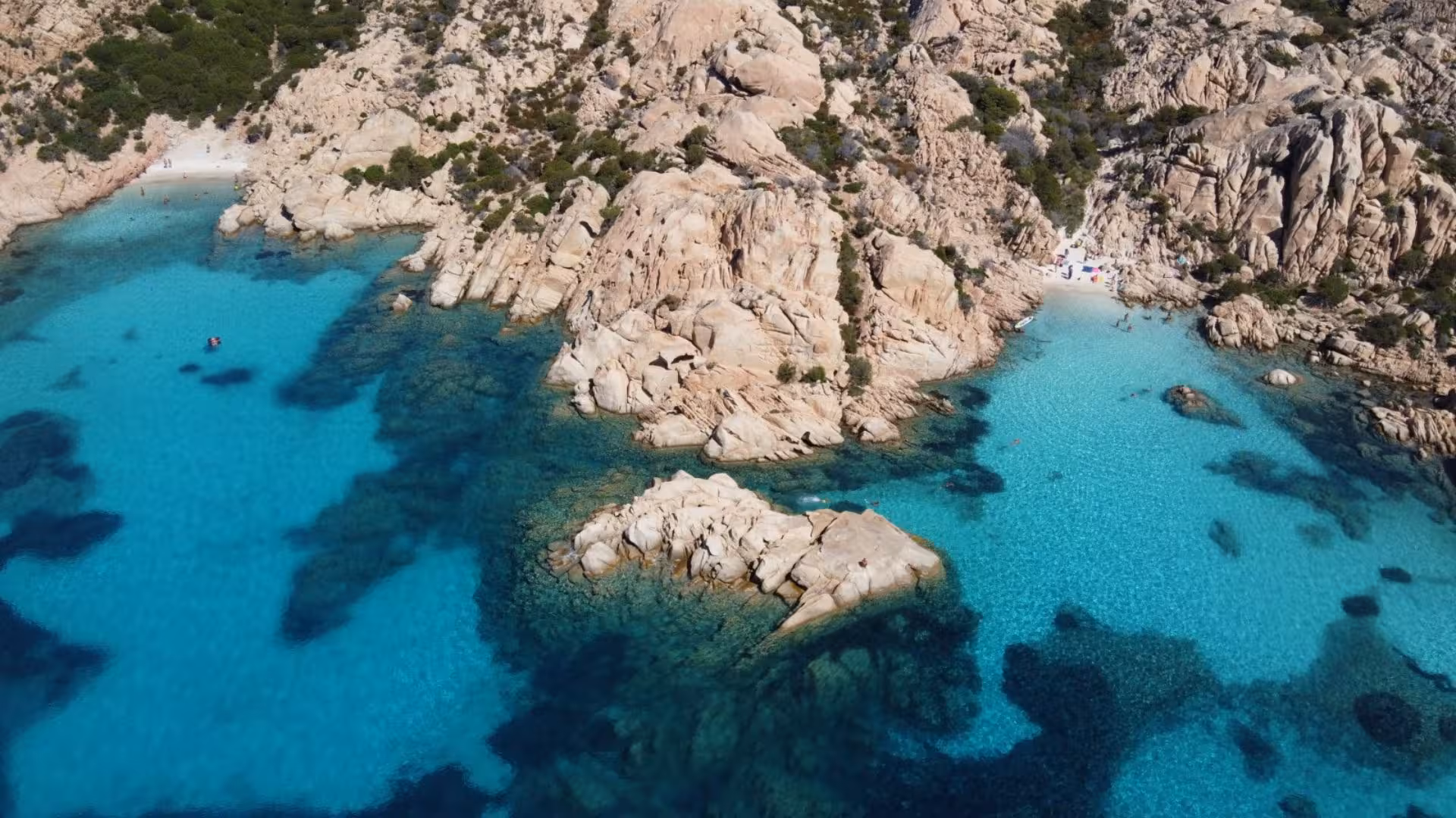 Aerial view of turquoise waters and rocky shores in La Maddalena Archipelago, perfect for a Cannigione sailboat tour.
