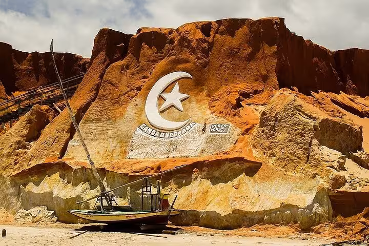Canoa Quebrada cliff landmark with fishing boat stop on a 3 beaches in 1 day coastal tour in Ceará