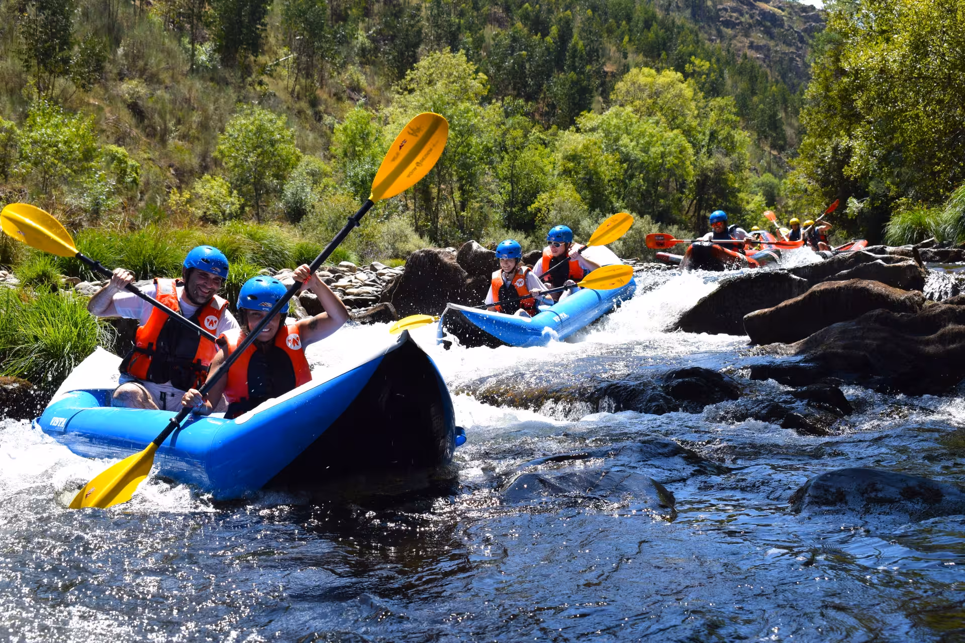 Guided canoe rafting on the Paiva River, Portugal, paddling through rocky rapids in lush forest scenery