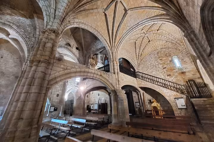 Majestic interior of a historic stone church with vaulted ceilings on Cantabria's coastal tour from Santander.