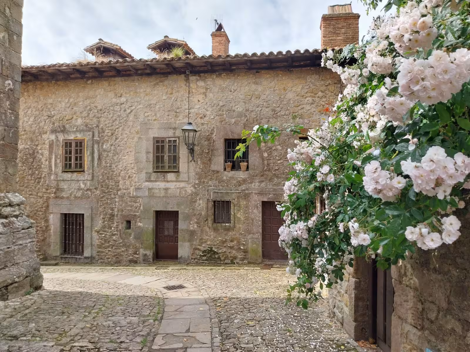 Charming stone house with blooming flowers in a picturesque village on Cantabria's coastal tour.