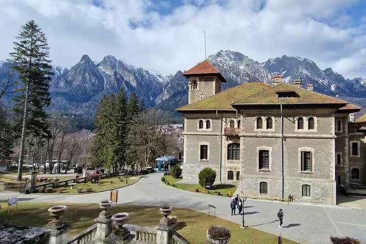 Cantacuzino Castle with snow-capped Bucegi Mountains backdrop near Brasov, Romania