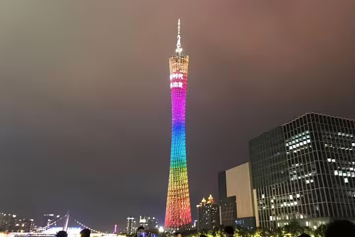 Canton Tower illuminated in vibrant colors at night, highlighting its iconic design during a Pearl River cruise.