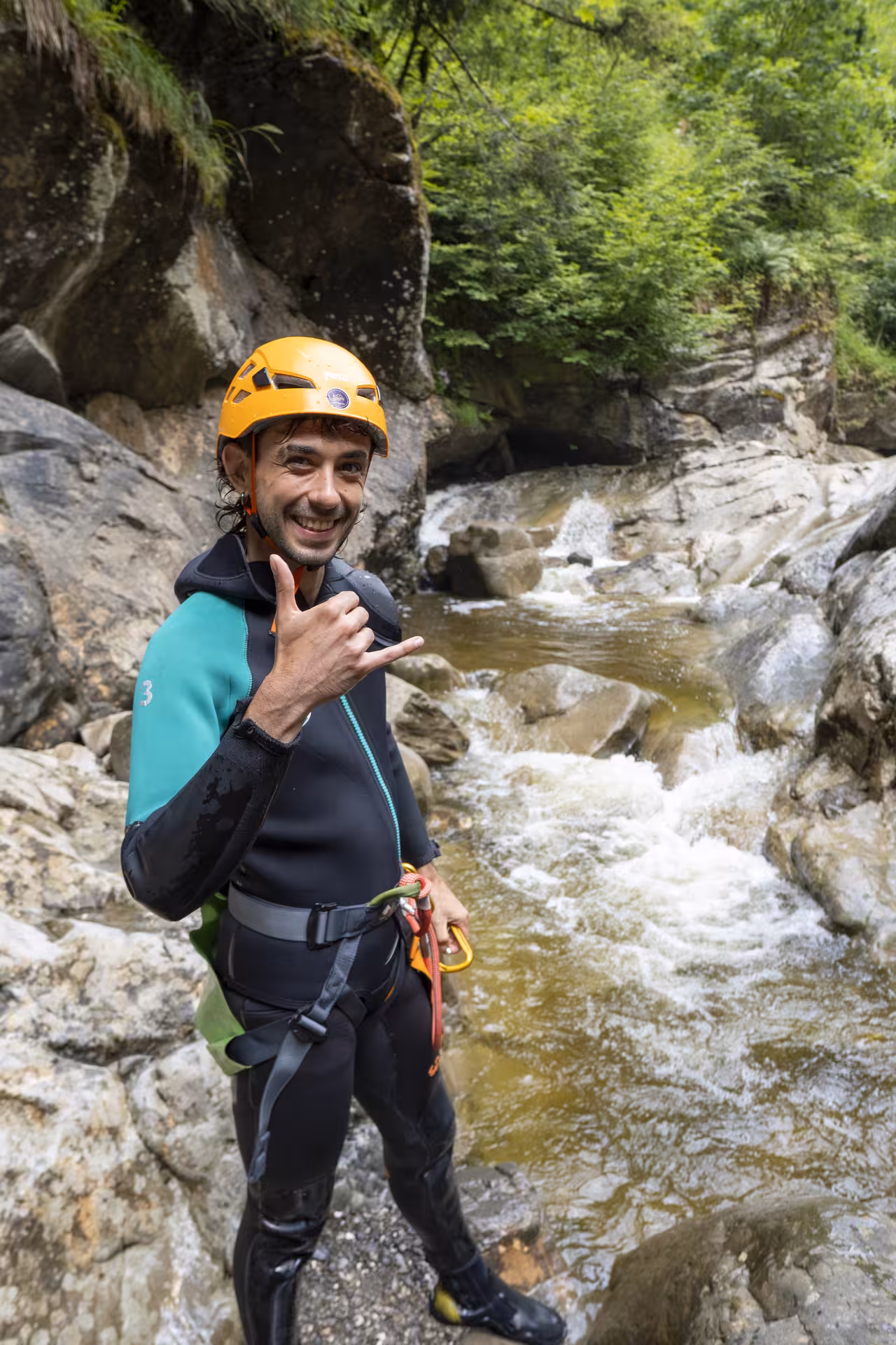 Smiling adventurer in wetsuit and helmet poses in Chli Schliere canyon, embodying excitement of Luzern canyoning.
