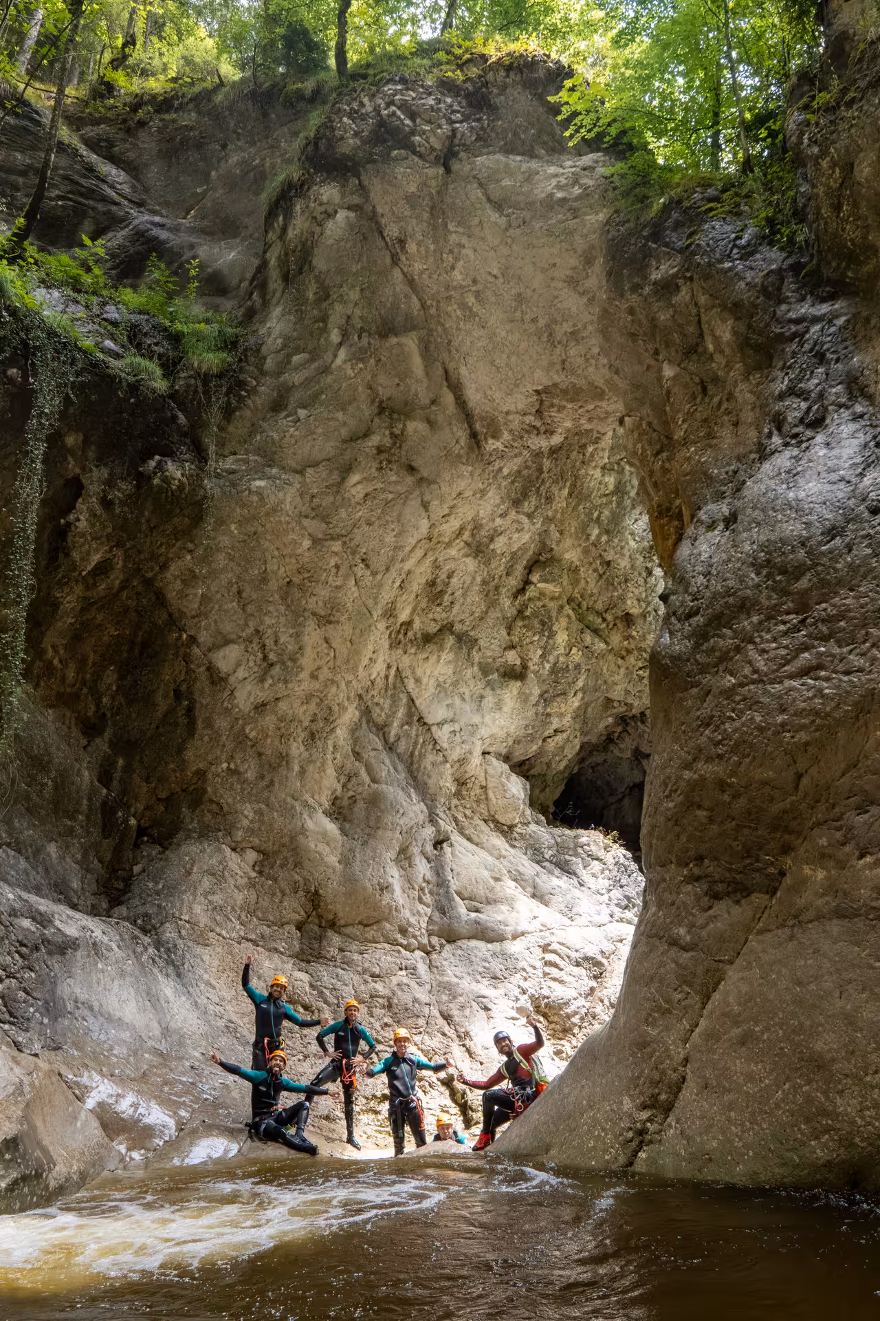 Adventurers in wetsuits celebrating in the rocky gorge of Chli Schliere, perfect for canyoning near Luzern.