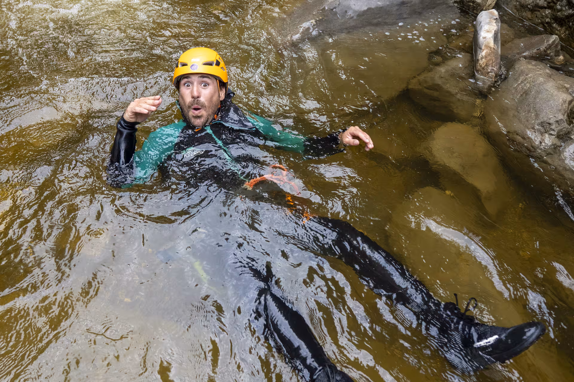 Canyoning participant in Chli Schliere, Luzern, floating in water with an expressive look during adventure tour.